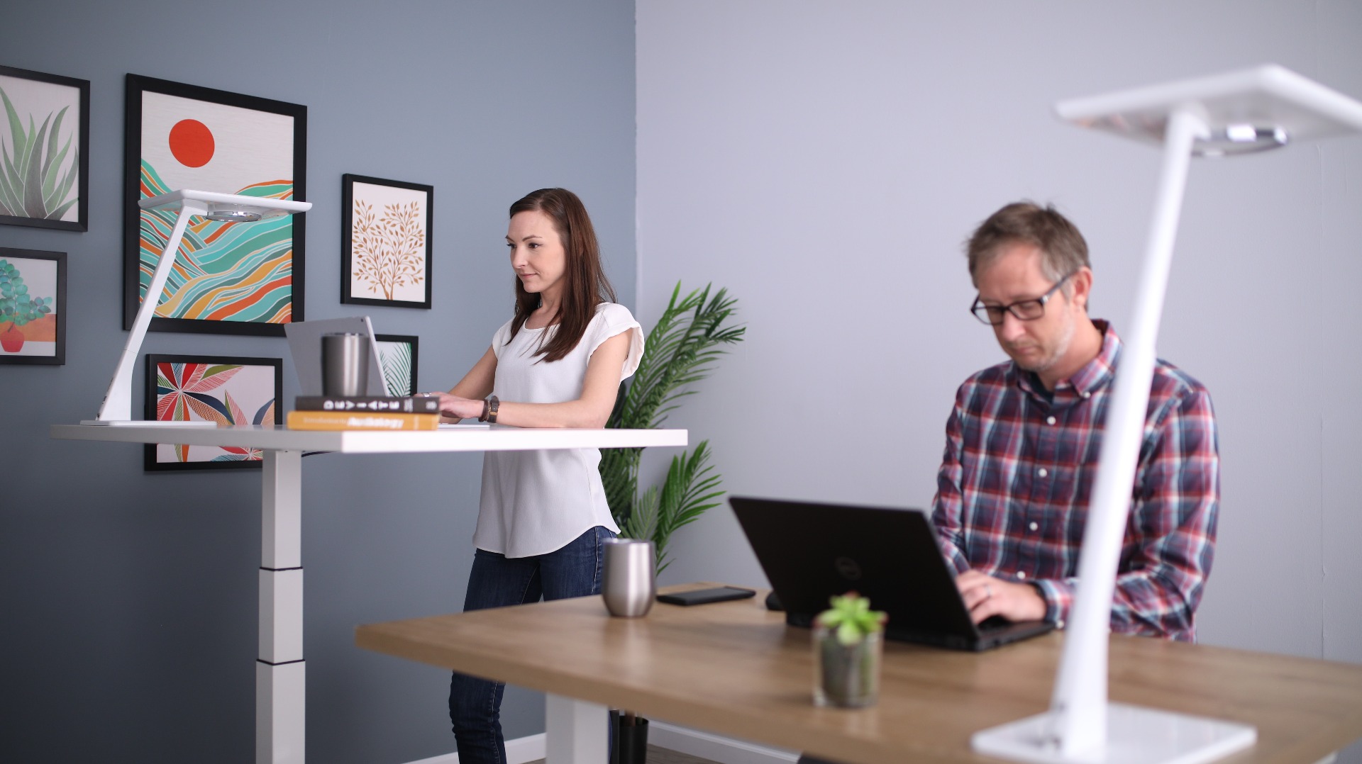 One person sitting, one standing at desks